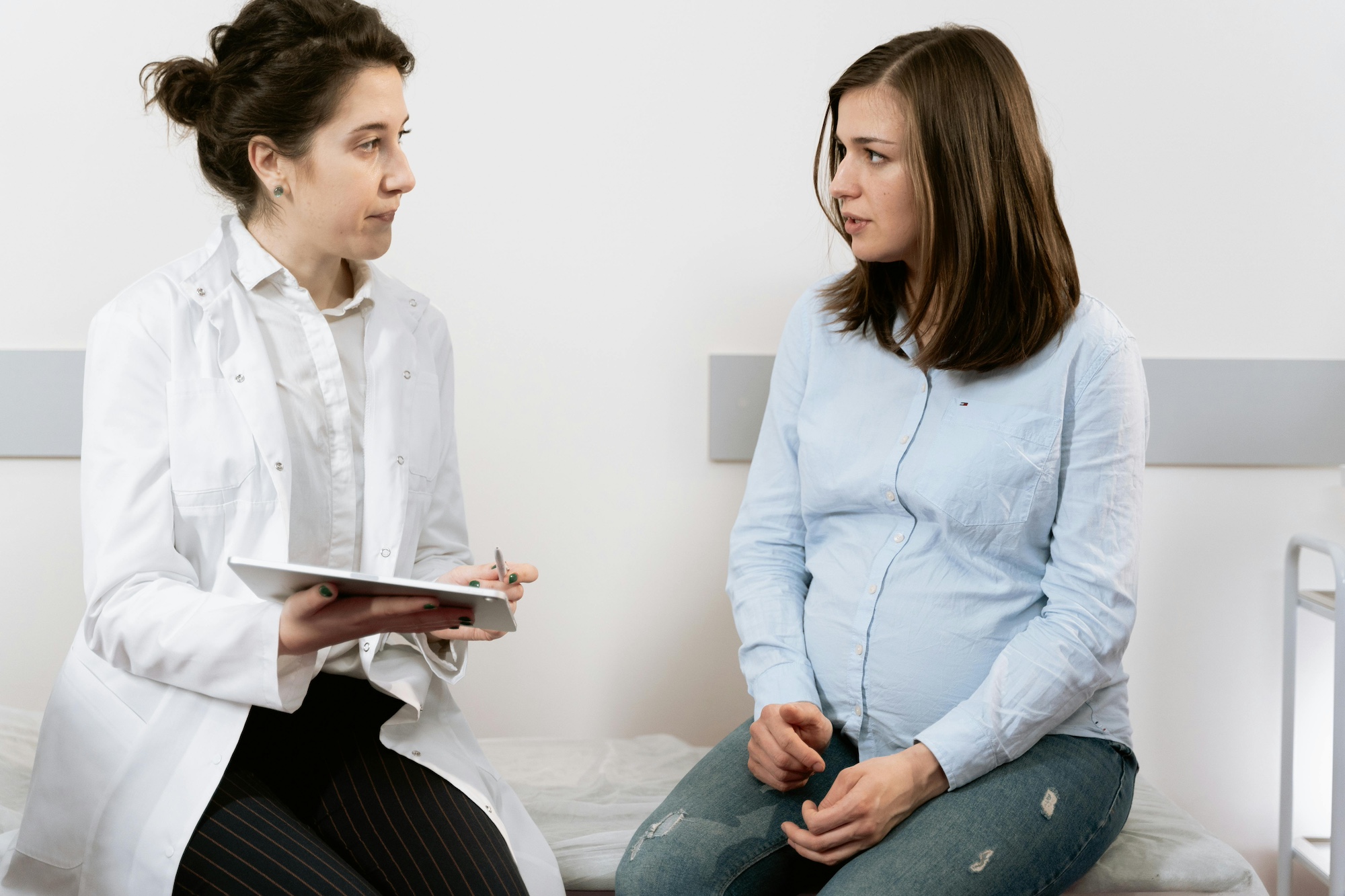 Female GP obstetrician providing prenatal care to a pregnant woman in a womens health care clinic.
